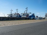 three tug boats docked by a building next to a road with a light on top