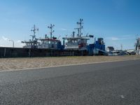 three tug boats docked by a building next to a road with a light on top