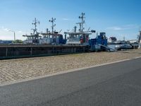 three tug boats docked by a building next to a road with a light on top