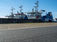 three tug boats docked by a building next to a road with a light on top