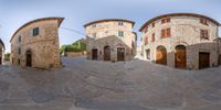 a view of several buildings in the middle of a courtyard area, with round windows