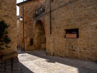 the sun is shining on this narrow cobblestone street with arched arches and a sign in the middle