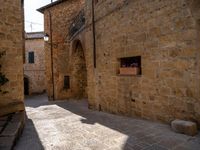 the sun is shining on this narrow cobblestone street with arched arches and a sign in the middle