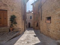 a narrow stone alley leading to a small wooden door on an old building with arches