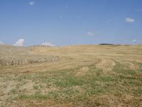 a farm field with freshly mowed grass under a partly blue sky in the distance