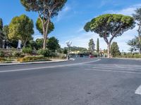 the empty street next to trees and buildings is shown in this image a car has stopped at a red stoplight in front of some buildings