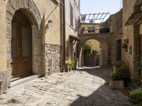 a view of a side street in the town center with stone buildings and an archway above it