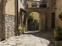 a view of a side street in the town center with stone buildings and an archway above it