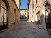 an old town has stone buildings and arched doorways on both sides of it and a small sidewalk running along the street