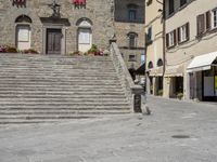 a stone city plaza with stairs and stairs on the right side of the path and buildings