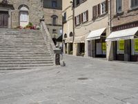 a stone city plaza with stairs and stairs on the right side of the path and buildings