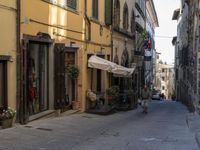 an old fashioned street is lined with buildings and cars driving past it in a row