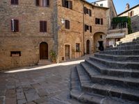 the stairs of a narrow cobblestone street lead up to an ancient building with multiple rooms