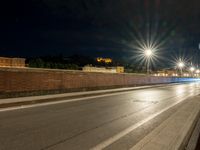 a long road with some traffic lights and a brick wall over it, which is illuminated in white