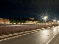 a long road with some traffic lights and a brick wall over it, which is illuminated in white