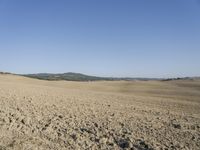 there is a lone red barn in the middle of a barren field of dirt and sparse grass