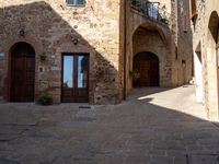 an old cobbled street in the middle of town with stone building facades and wooden doors