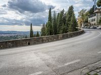 a curve is near a wall on the side of a road as cars line the curb