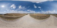 a road running across a dry grass field in a panoramic image taken from 360 - camera