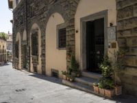 a street filled with potted plants and old stone buildings on both sides of it