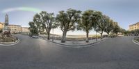 a 360 view of a street with trees in it, a statue and buildings, and a man riding a motorcycle