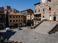 an old stone square in a city with buildings and lots of flowers growing on the steps