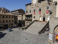 an old stone square in a city with buildings and lots of flowers growing on the steps