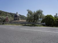 a view of a country road in the mountains with a church on it and a steep hill behind