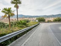 an old winding highway is leading to a large town with palm trees in the distance