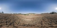 this is a 360 - lens photo of an empty field and hills, viewed through an orange fence