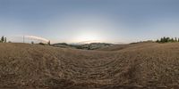 a 360 - vr photo of a landscape of hills, dirt and grass and sunbursted sky