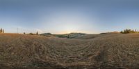 a wide - angle photo of a desert landscape during the daytime, with the sun peaking through