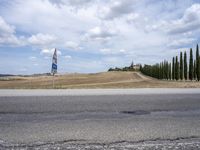 a street sign is in front of a beautiful countryside scene with cypress trees and hills