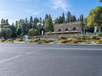 an empty street in front of a building near a forest and a large road sign