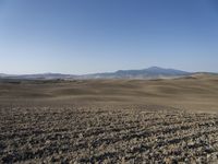 the hills are empty and visible in this landscape of sparse farmland, and a dirt road leading