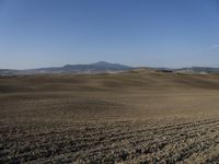 the hills are empty and visible in this landscape of sparse farmland, and a dirt road leading