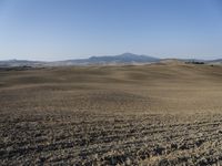 the hills are empty and visible in this landscape of sparse farmland, and a dirt road leading