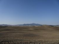 the hills are empty and visible in this landscape of sparse farmland, and a dirt road leading