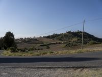 a street view shows the landscape and hills below on the road that leads to town