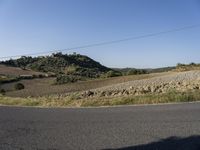 a street view shows the landscape and hills below on the road that leads to town