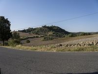 a street view shows the landscape and hills below on the road that leads to town