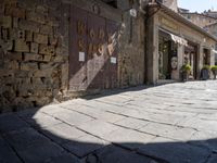 a shadow is cast on the ground in the foreground, there is an old building next to some brick walls