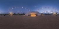 a farm is lit up at twilight with lots of string lights around the barn and building