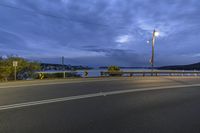 the street lights shine in the twilight light on a dark cloudy day over a bay