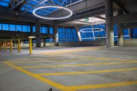 a view of an open parking lot at twilight with yellow lines on the ground, a streetlight and some pillars