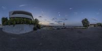 an upside down view of a skateboard park at twilight, with the city in the background