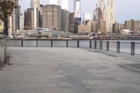 empty sidewalk with view of city skyline from near river bank, at twilight time with sunlight