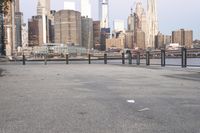 empty sidewalk with view of city skyline from near river bank, at twilight time with sunlight