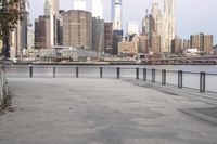 empty sidewalk with view of city skyline from near river bank, at twilight time with sunlight