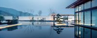 the interior of a modern house with a water view at twilight from an indoor pool